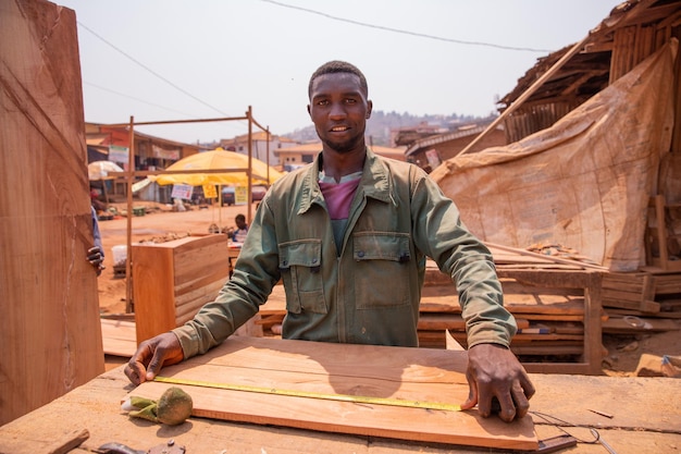 Carpintero en un pueblo africano tomando medidas para hacer un mueble