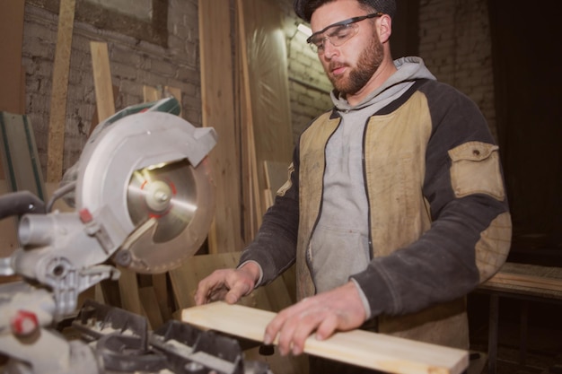 Foto carpintero en ropa de trabajo trabajando en madera en carpintería