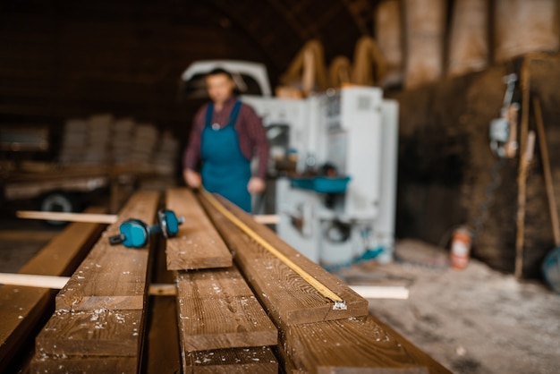 Foto carpintero con tableros de cinta métrica, máquina para trabajar la madera, industria maderera, carpintería. procesamiento de madera en fábrica, aserrado forestal en aserradero