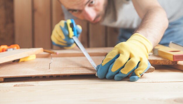 Foto carpintero con tablón de madera de medición de regla.