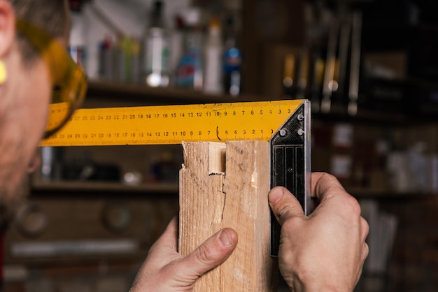 Un carpintero trabaja en un taller de muebles con varias herramientas y una tabla.