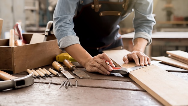 Carpintero trabajando con equipo sobre mesa de madera en carpintería.
