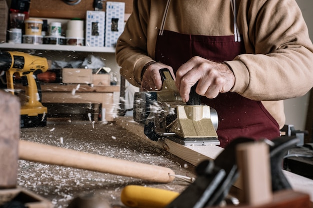 Carpintero trabajando la madera con un cepillo eléctrico