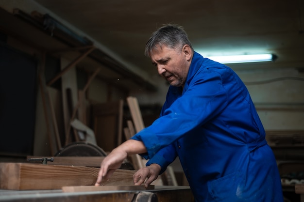 Carpintero trabajando en su taller, procesamiento de madera en una máquina de carpintería