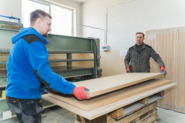 Carpinteros llevando paneles de madera en el taller