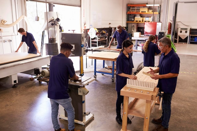 Carpinteros trabajando en máquinas en taller de carpintería ocupado