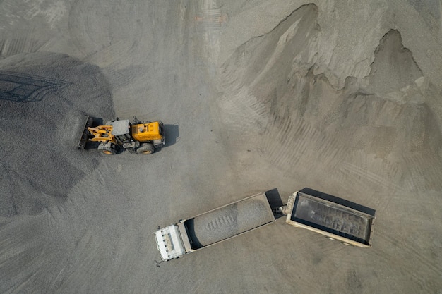 Carregadores de areia estão jogando pedras em caminhões basculantes