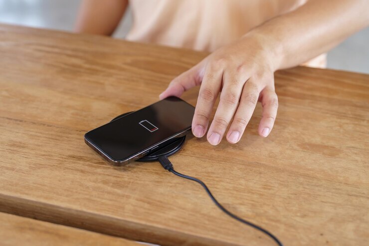 Foto carregando a bateria do telefone celular com dispositivo de carregamento sem fio na mesa smartphone carregando em uma base de carregamento celular perto do carregador sem fio conceito de tecnologia de estilo de vida moderno