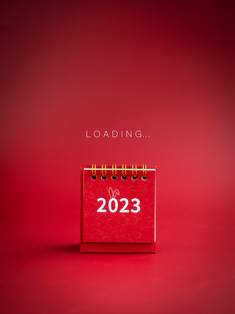 Foto carregando para fundo de feliz natal e feliz ano novo 2023 o texto de carregamento aparece no pequeno calendário de mesa vermelho com números de 2023 anos no estilo vertical minimalista de fundo vermelho