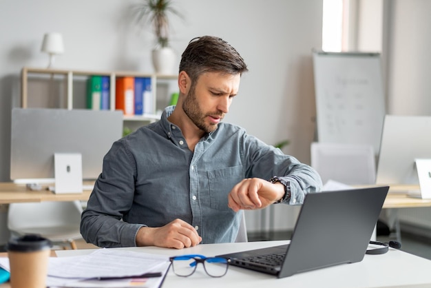 Carreira empresarial e gestão de tempo empresário maduro usando laptop e verificando o tempo olhando para