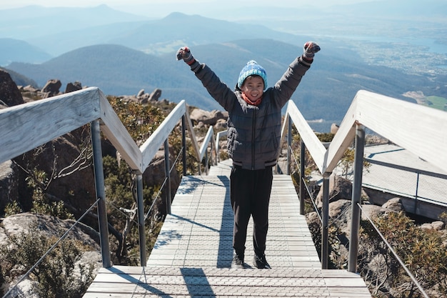 Carrera mezclada, asiático, interpolación, niño, posición, con, mano arriba, en la cima de la montaña