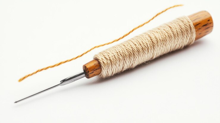 Un carrete de hilo con una aguja mango de madera hilo beige