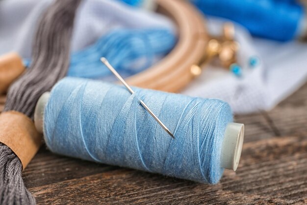 Foto carrete de hilo de coser con aguja en la mesa