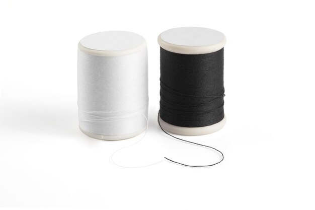 Carrete de hilo de coser blanco y negro sobre un blanco