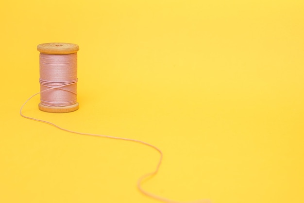 Foto un carrete de hilo rosa sobre un fondo amarillo.