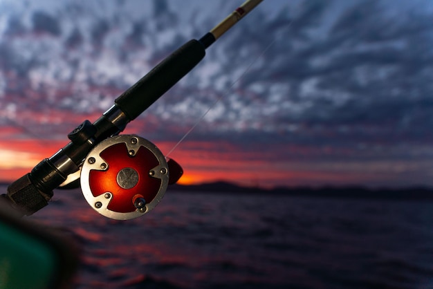 Carretel de pesca em alto mar em um barco durante o nascer do sol