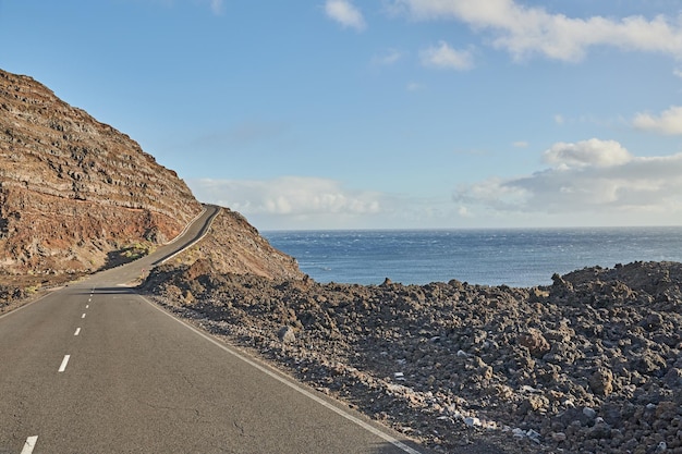 Carretera de alquitrán o calle que conduce a montañas escénicas con vistas al mar durante un viaje de verano en La Palma Islas Canarias España Paisaje de un puerto de montaña rocoso con nubes de cielo azul y espacio para copiar