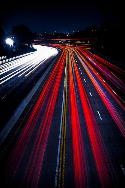 Una carretera ancha con rastros de semáforos brillantes abstractos por la noche, fondo vertical