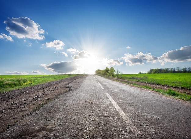 Carretera asfaltada en el campo y la luz del sol