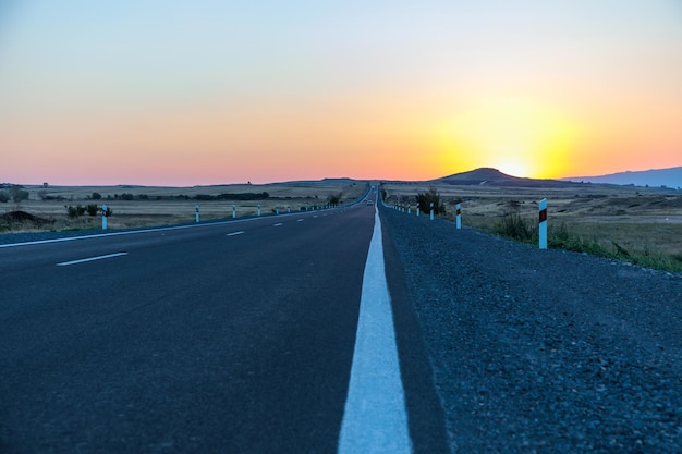 Carretera asfaltada con colorida puesta de solxA