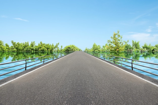 Carretera asfaltada con lago y fondo de cielo azul