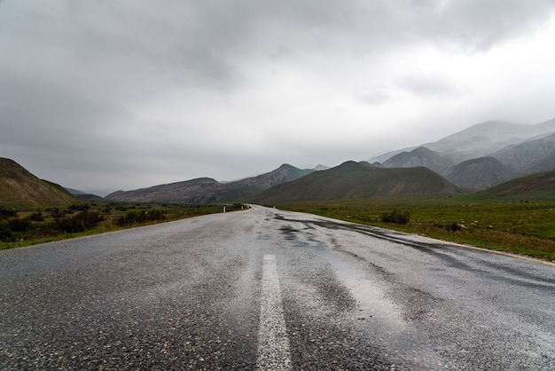 Carretera asfaltada mojada en zona montañosa