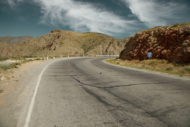 Carretera asfaltada y rocas bajo fondo de cielo