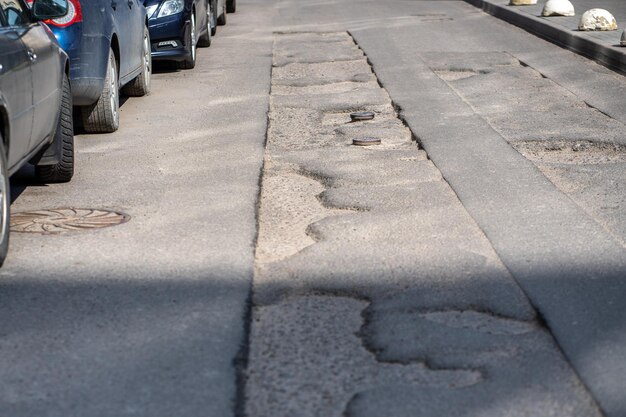 Carretera asfaltada rota en la ciudad y reparaciones inoportunas en el estacionamiento reparaciones de carreteras asfaltadas con baches