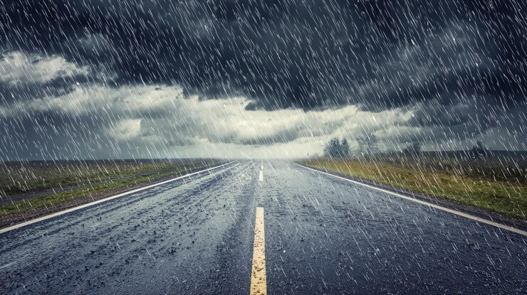 Carretera de asfalto húmeda bajo fuertes lluvias y nubes oscuras