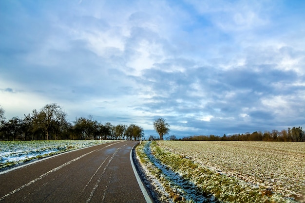 Carretera de asfalto negro vacío entre campos verdes