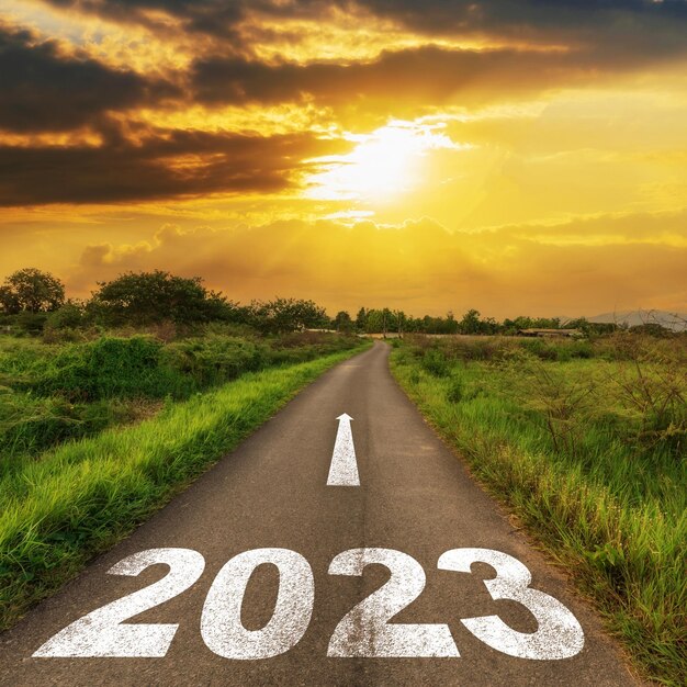 Foto carretera de asfalto vacía y concepto de nuevo año 2023 conduciendo en un camino vacío hacia los objetivos 2023 con puesta de sol