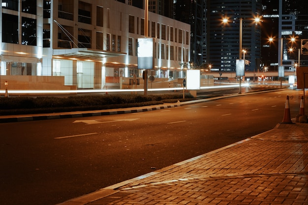 Carretera de asfalto vacía con edificios modernos en la noche en dubai