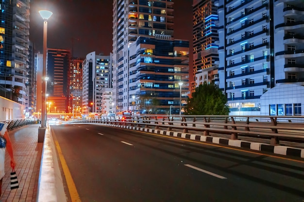 Carretera de asfalto vacía con edificios modernos en la noche en dubai