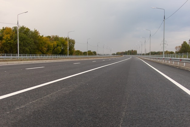 Foto carretera de asfalto vacía con farolas al atardecer.