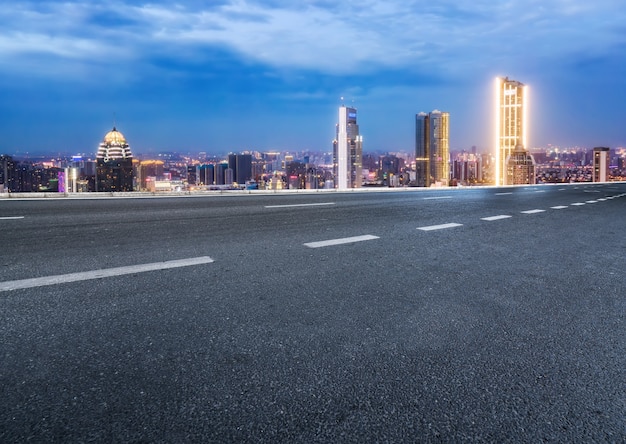 Carretera de asfalto vacía y horizonte de la ciudad y paisaje de construcción, China.