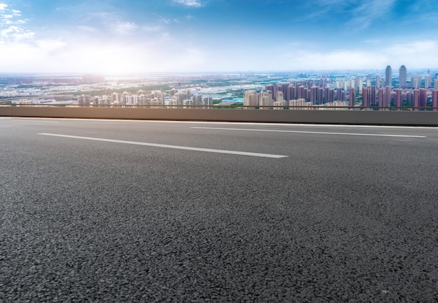 Carretera de asfalto vacía y horizonte de la ciudad y paisaje de construcción, China.