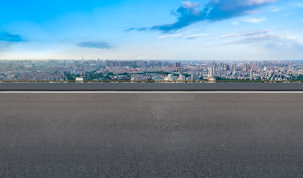 Carretera de asfalto vacía y horizonte de la ciudad y paisaje de construcción, China.