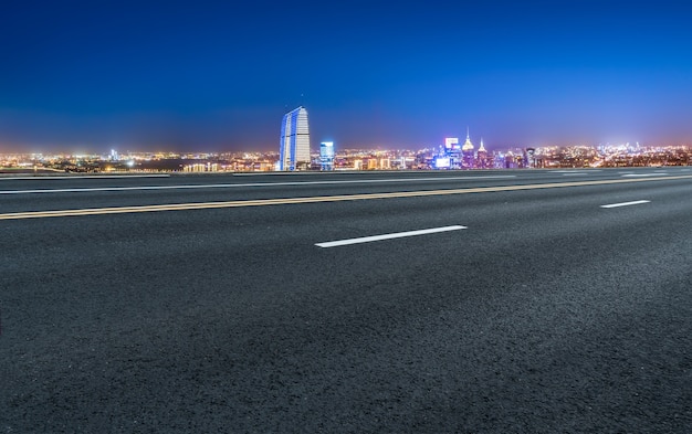 Carretera de asfalto vacía y horizonte de la ciudad y paisaje de construcción, China.