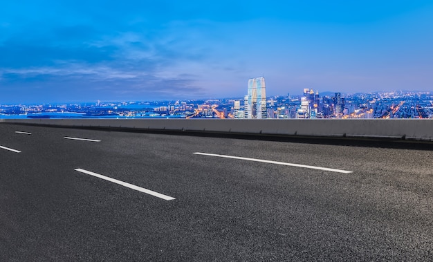 Carretera de asfalto vacía y horizonte de la ciudad y paisaje de construcción, China.