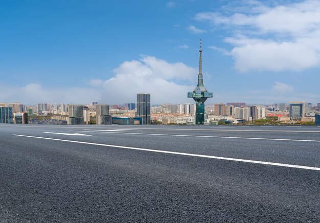 Carretera de asfalto vacía y horizonte de la ciudad y paisaje de construcción, China.