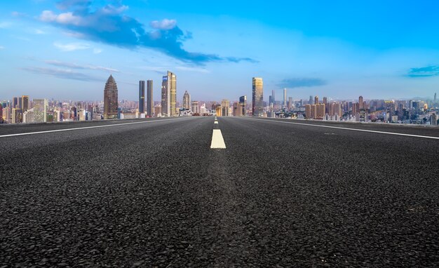 Carretera de asfalto vacía y horizonte de la ciudad y paisaje de construcción, China.