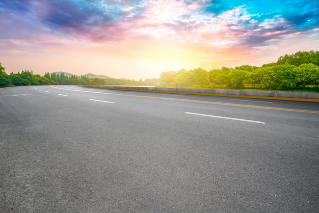 La carretera de asfalto vacía y el paisaje natural bajo el cielo azul