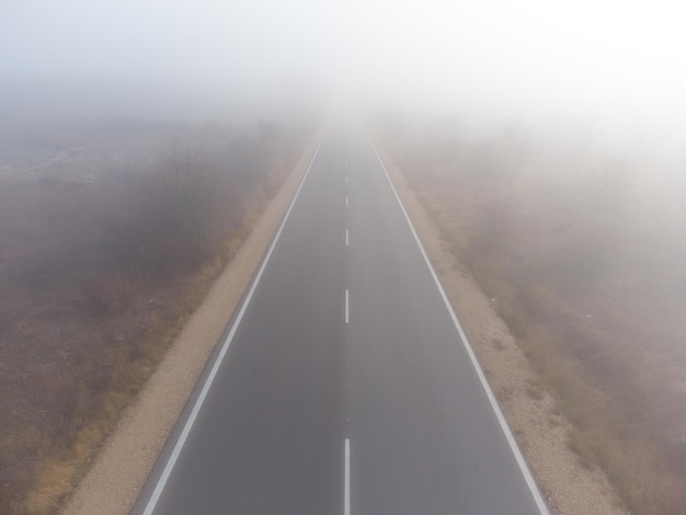 Carretera de asfalto en una vista aérea del bosque de niebla otoñal