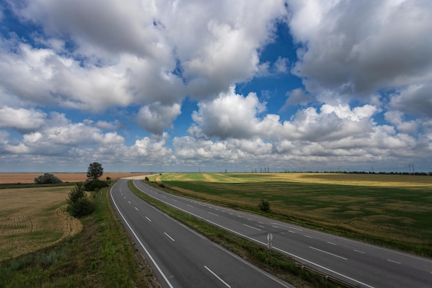 Foto carretera entre campos bajo un hermoso cielo con nubes blancas