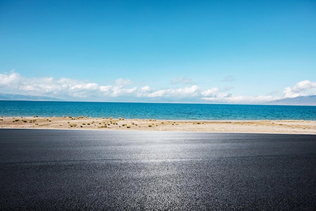 Una carretera con un cielo azul y el mar de fondo