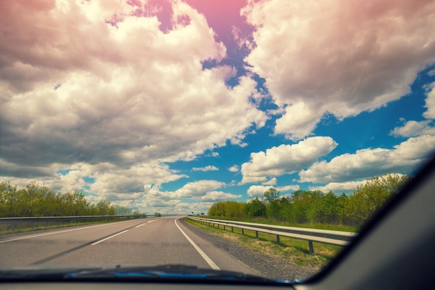 Carretera con cielo nublado en verano Vista de la carretera a través del parabrisas