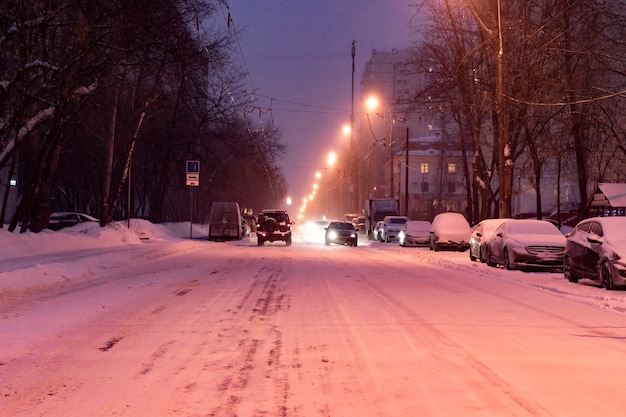 Carretera de la ciudad cubierta de nieve con coches al margen en la temporada de invierno