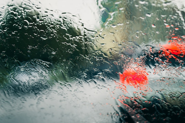 Carretera de la ciudad vista a través de gotas de lluvia en el parabrisas del coche