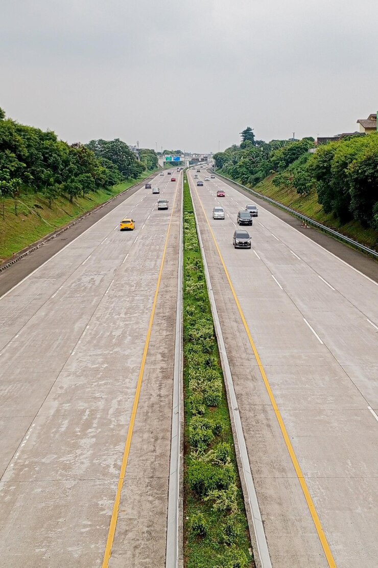 una carretera con coches conduciendo en ella y los árboles en el lado