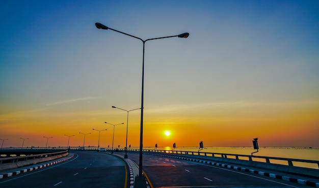 Carretera costera curva con farola al atardecer